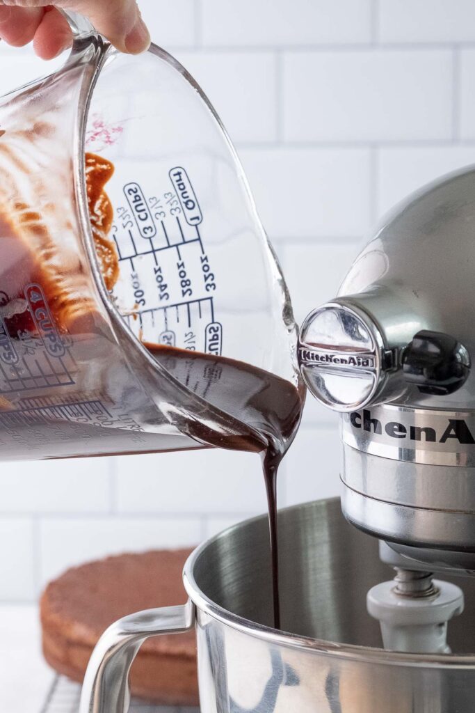 pouring melting chocolate into a silver mixing bowl