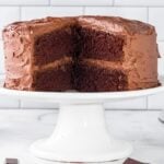 chocolate cake on a white can stand with a large section but out