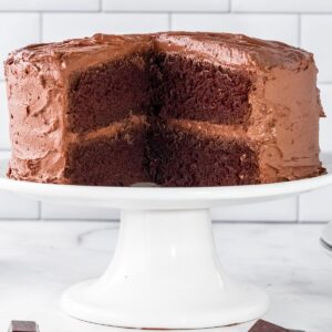 chocolate cake on a white can stand with a large section but out