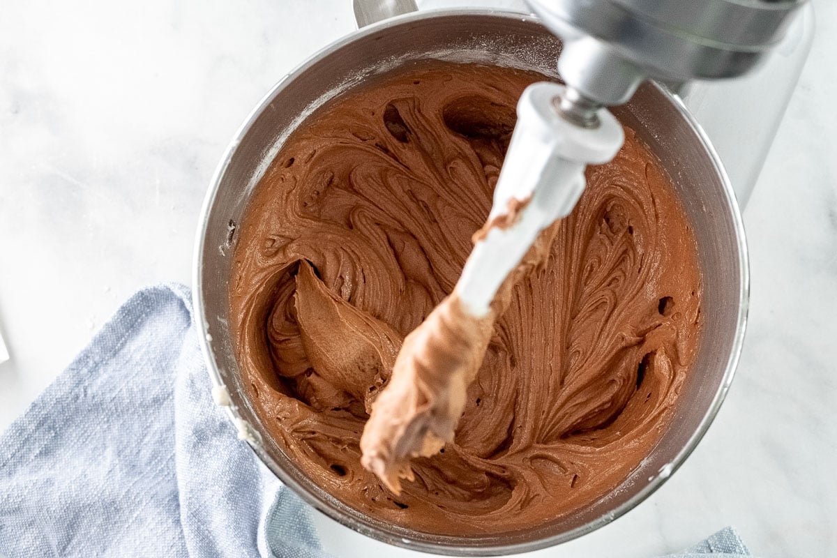 chocolate frosting in a stand mixer bowl with the white paddle attachment over it