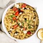 closeup of greek pasta salad with rotini pasta, feta cheese, olives and tomatoes