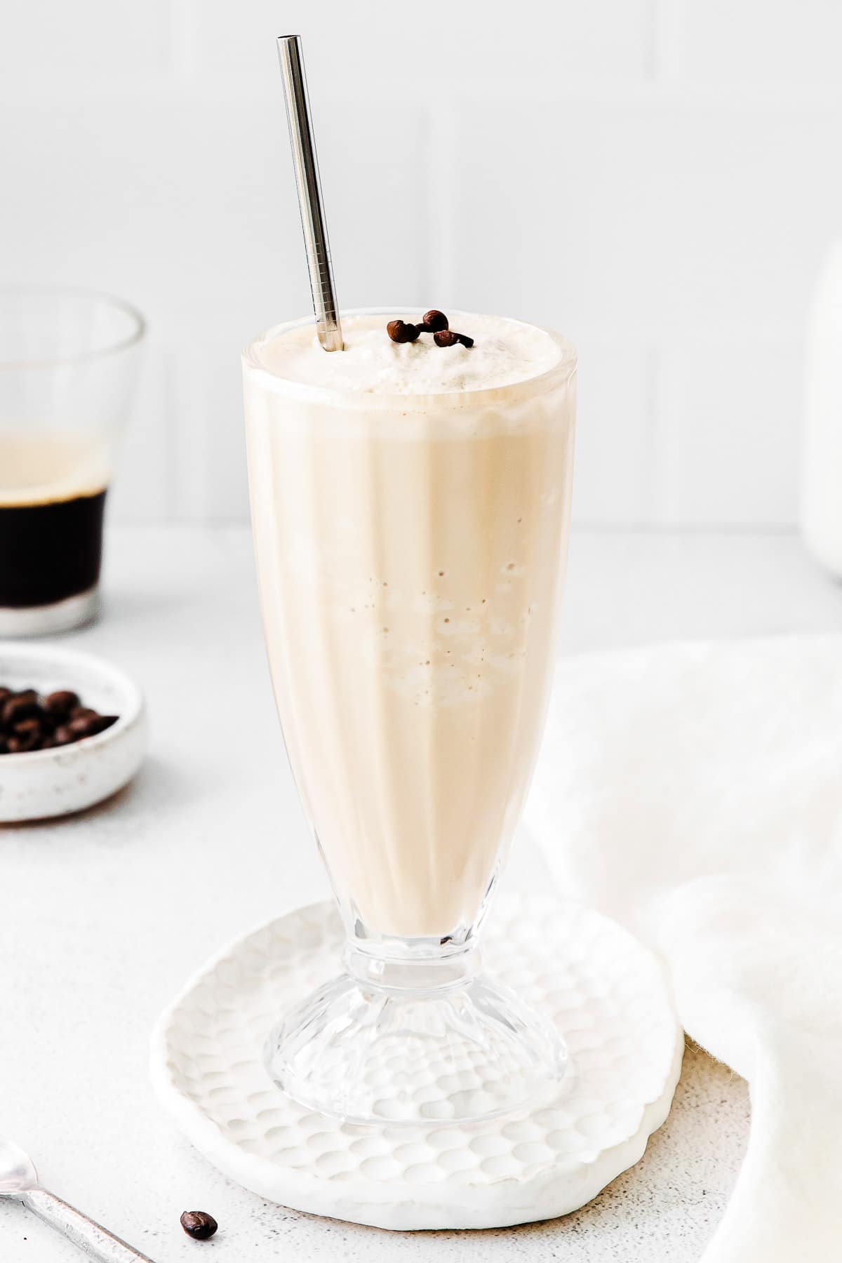 closeup of a milkshake a tall stemmed glass on a white coaster