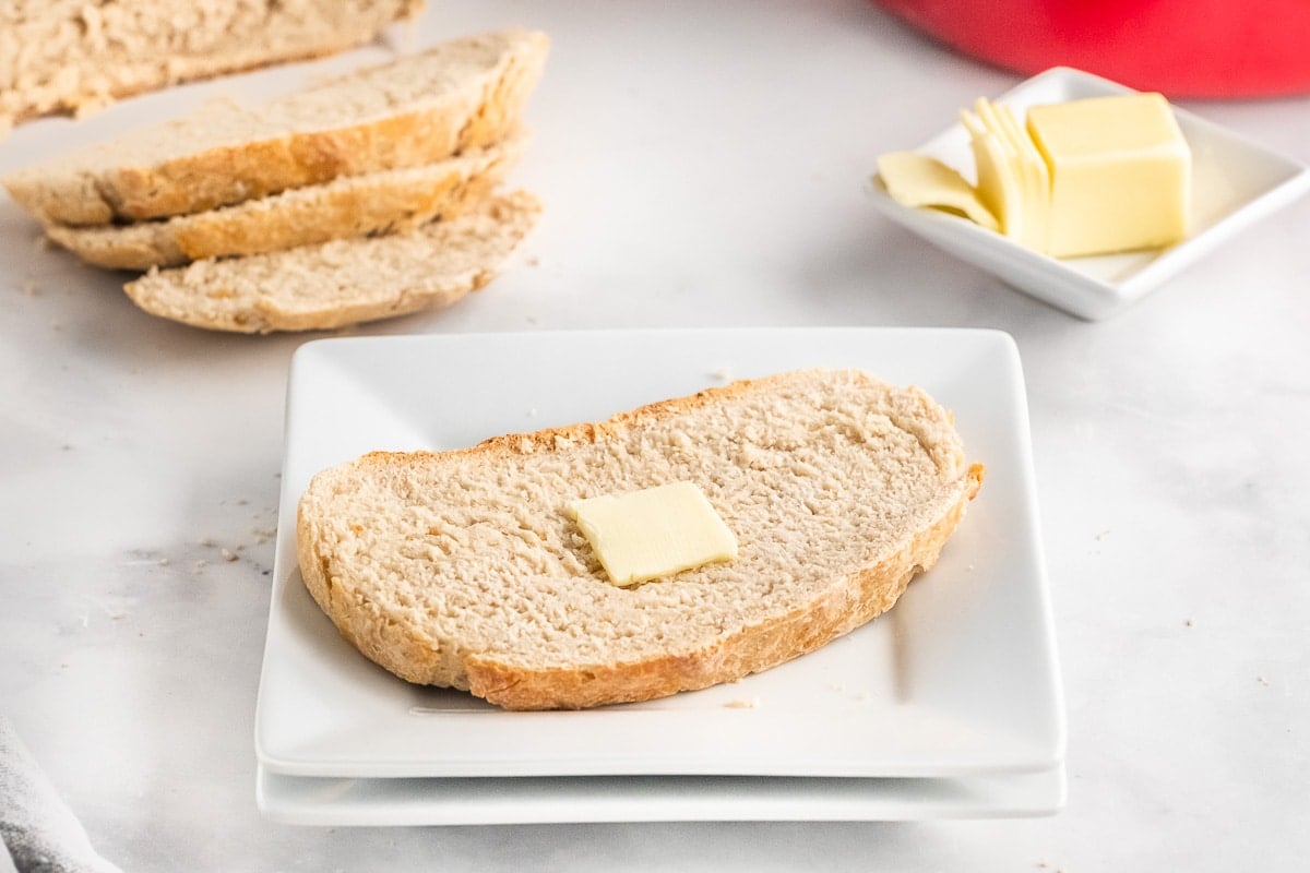 white square plate with a slice of bread with butter