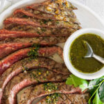 sliced steak with chimichurri sauce drizzled on top