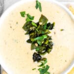 a white bowl with queso cheese dip with diced poblano peppers on top