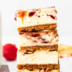 closeup of a stack of four strawberry cheesecake bars on a wood cutting board with text overlay that reads Strawberry Cheesecake Bars