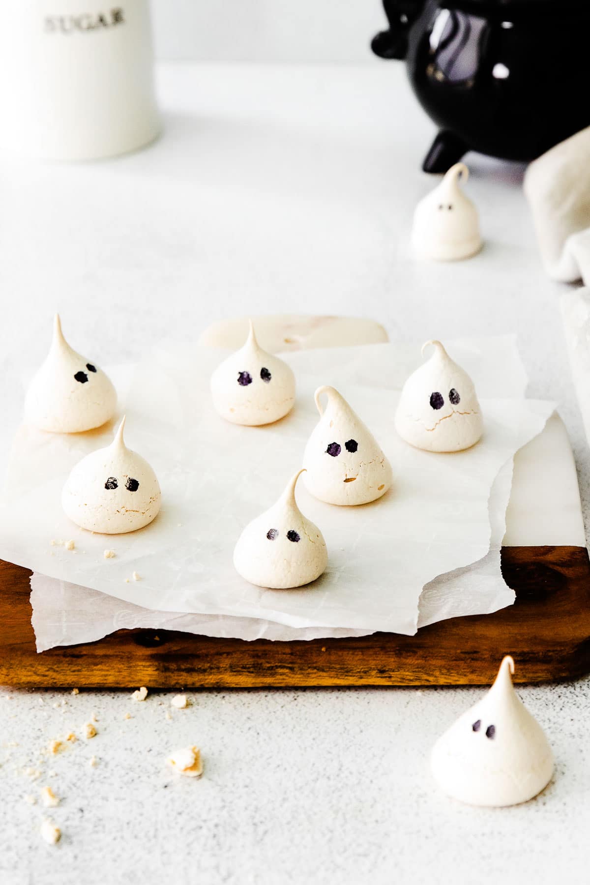 several meringues with black eyes on a wood cutting board with white parchment paper