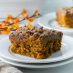 closeup of a slice of pumpkin coffee cake with crumb topping in a white plate