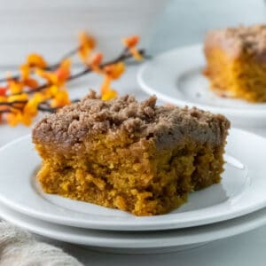 closeup of a slice of pumpkin coffee cake with crumb topping in a white plate