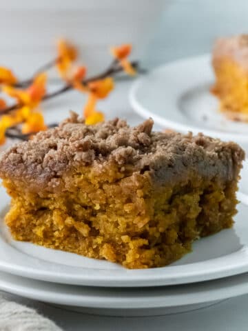 closeup of a slice of pumpkin coffee cake with crumb topping in a white plate