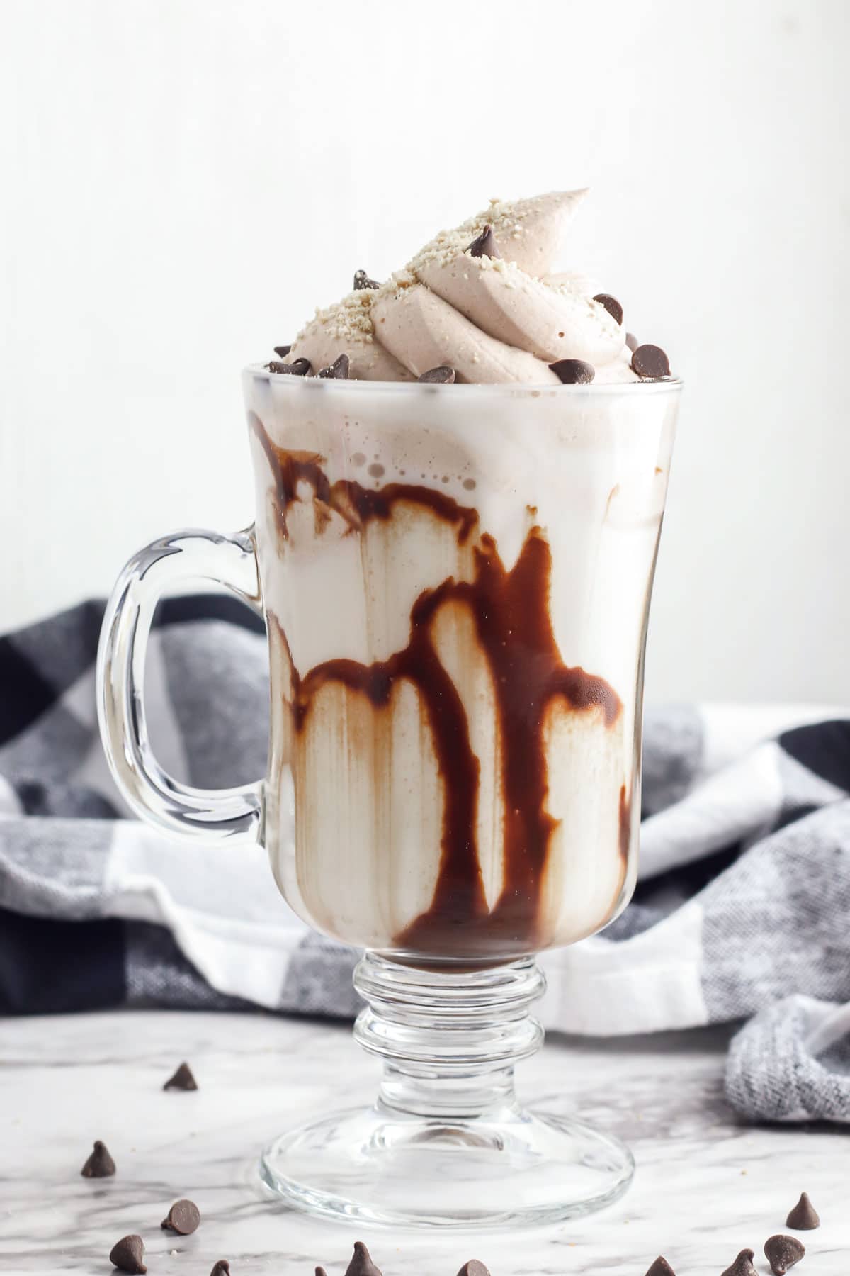 tall stemmed glass with a handle with a swirl of whipped chocolate cream topped with chocolate chips