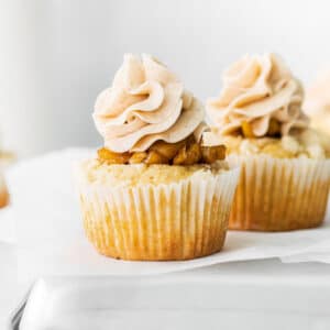 closeup of a vanilla cupcake topped with diced apple pie filling and buttercream frosting