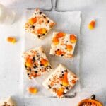 closeup of 3 squares of white fudge with candy corn and orange and black sprinkles