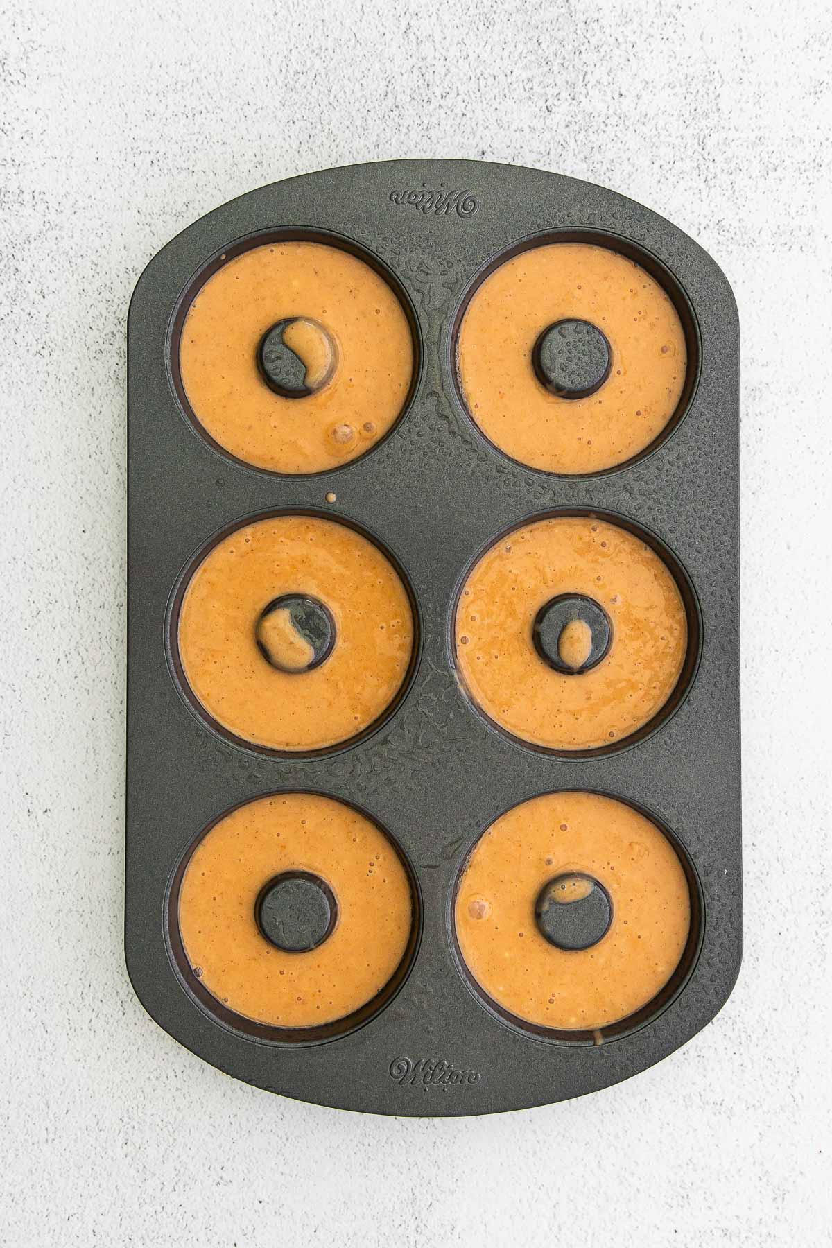six pumpkin donuts baked in a donut pan