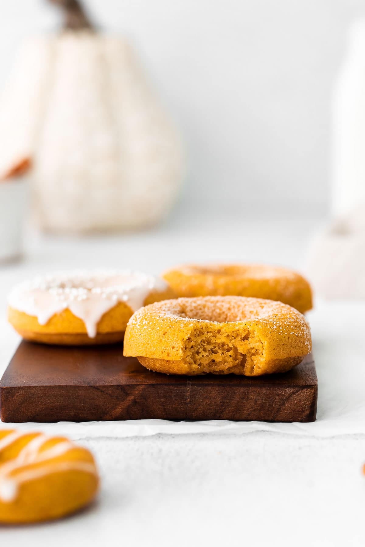 pumpkin spiced donut with a bite taken out on a wood board