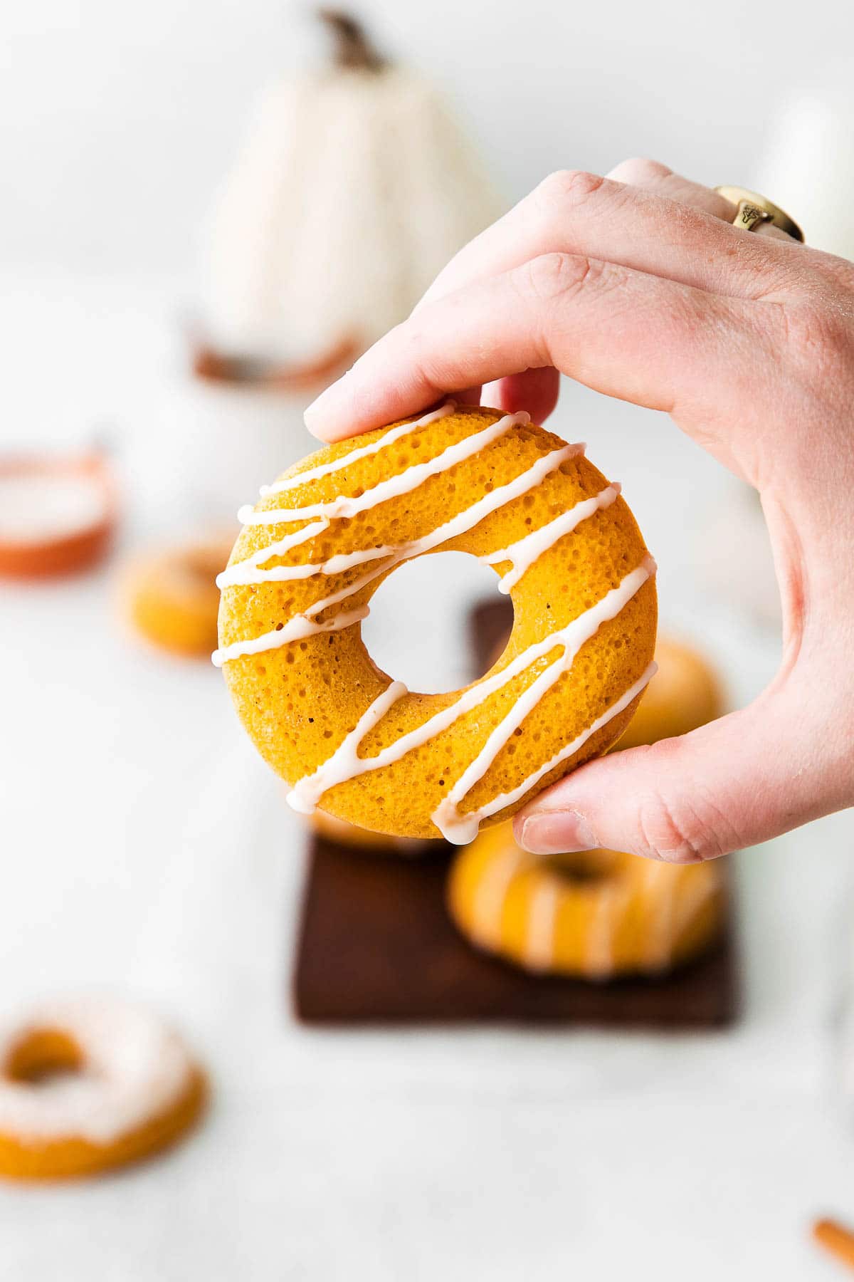 hand holding a vanilla drizzled pumpkin donut