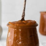 a glass jar filled with pumpkin butter with an antique spoon sticking out of