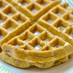 closeup of two waffles with syrup on top on a white plate