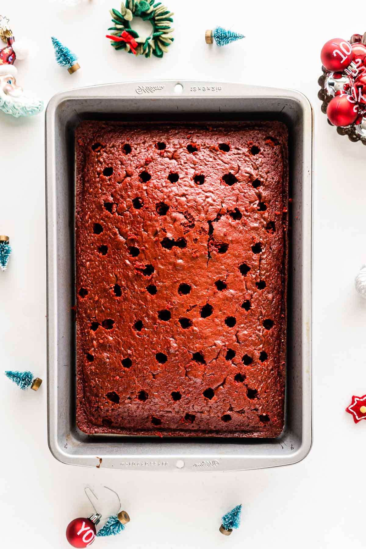 baking pan with red velvet cake with holed poked in it