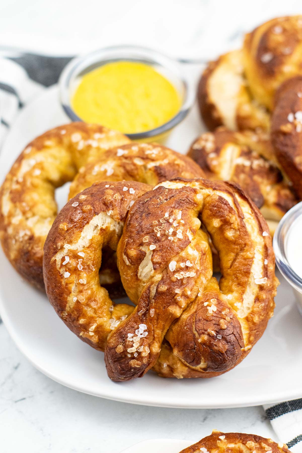 closeup of several soft pretzels on a white plate