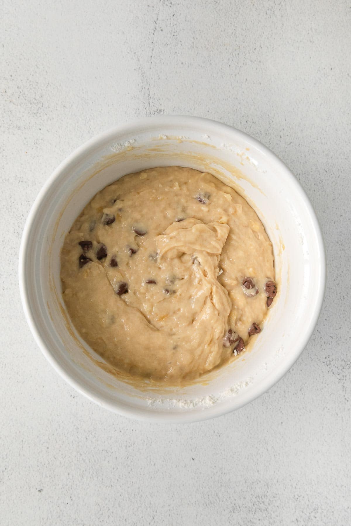 banana bread batter with chocolate chips in a white mixing bowl