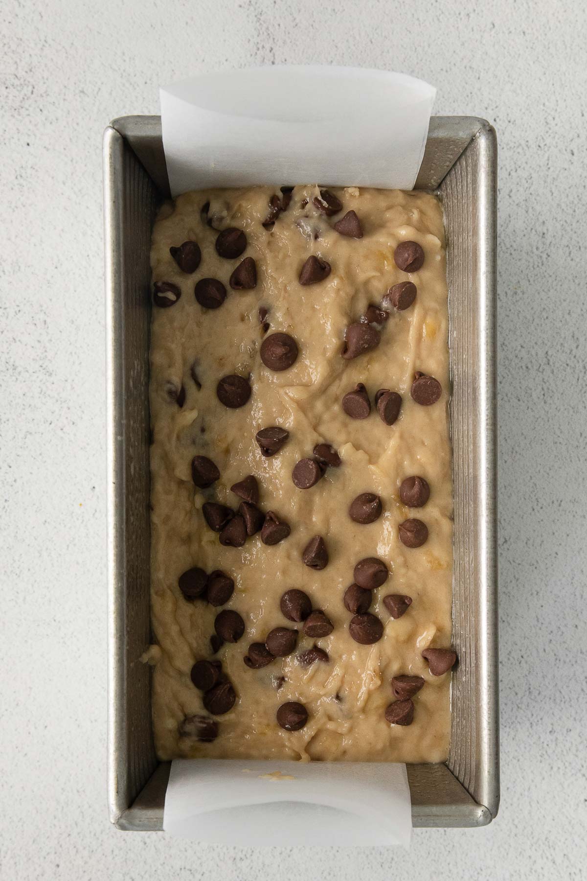 metal loaf pan with bread batter topped with chocolate chips