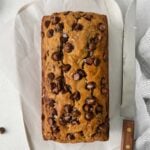 loaf of banana bread on parchment paper topped with chocolate chips
