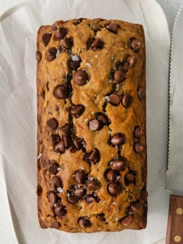 loaf of banana bread on parchment paper topped with chocolate chips