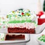 closeup of a spatula holding a slice of Christmas lasagna dessert with red white and green layers