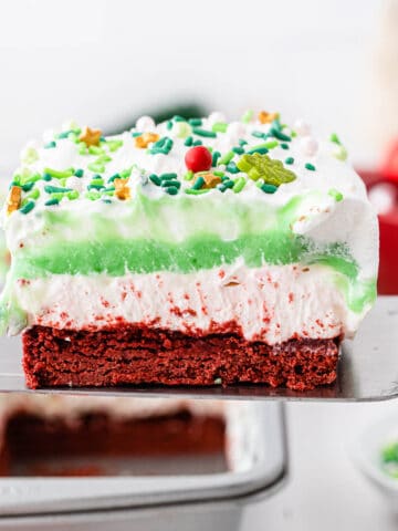 closeup of a spatula holding a slice of Christmas lasagna dessert with red white and green layers