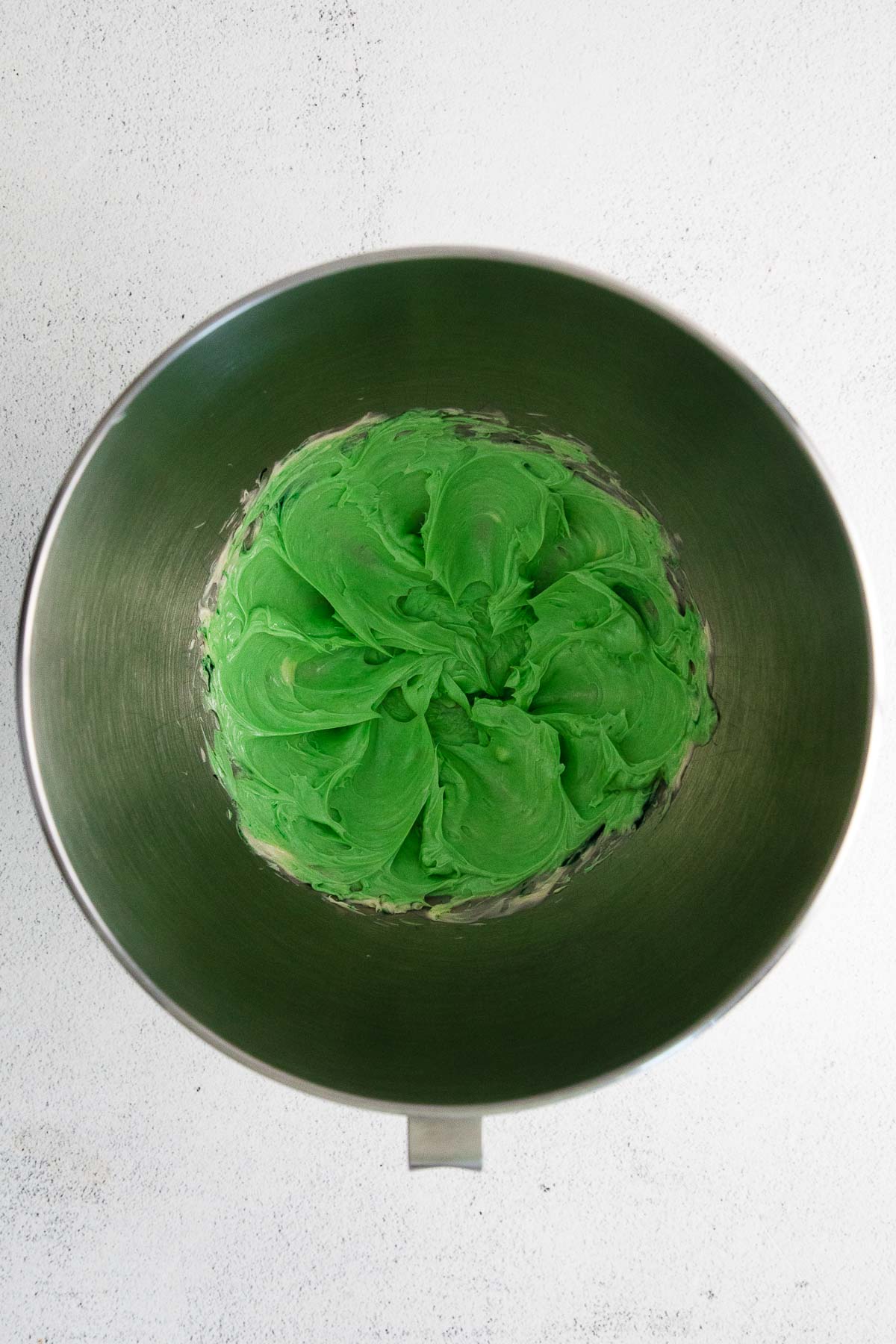 green colored whipped butter in a stainless steel mixing bowl
