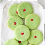 several green sugar cookies with a red heart in the center