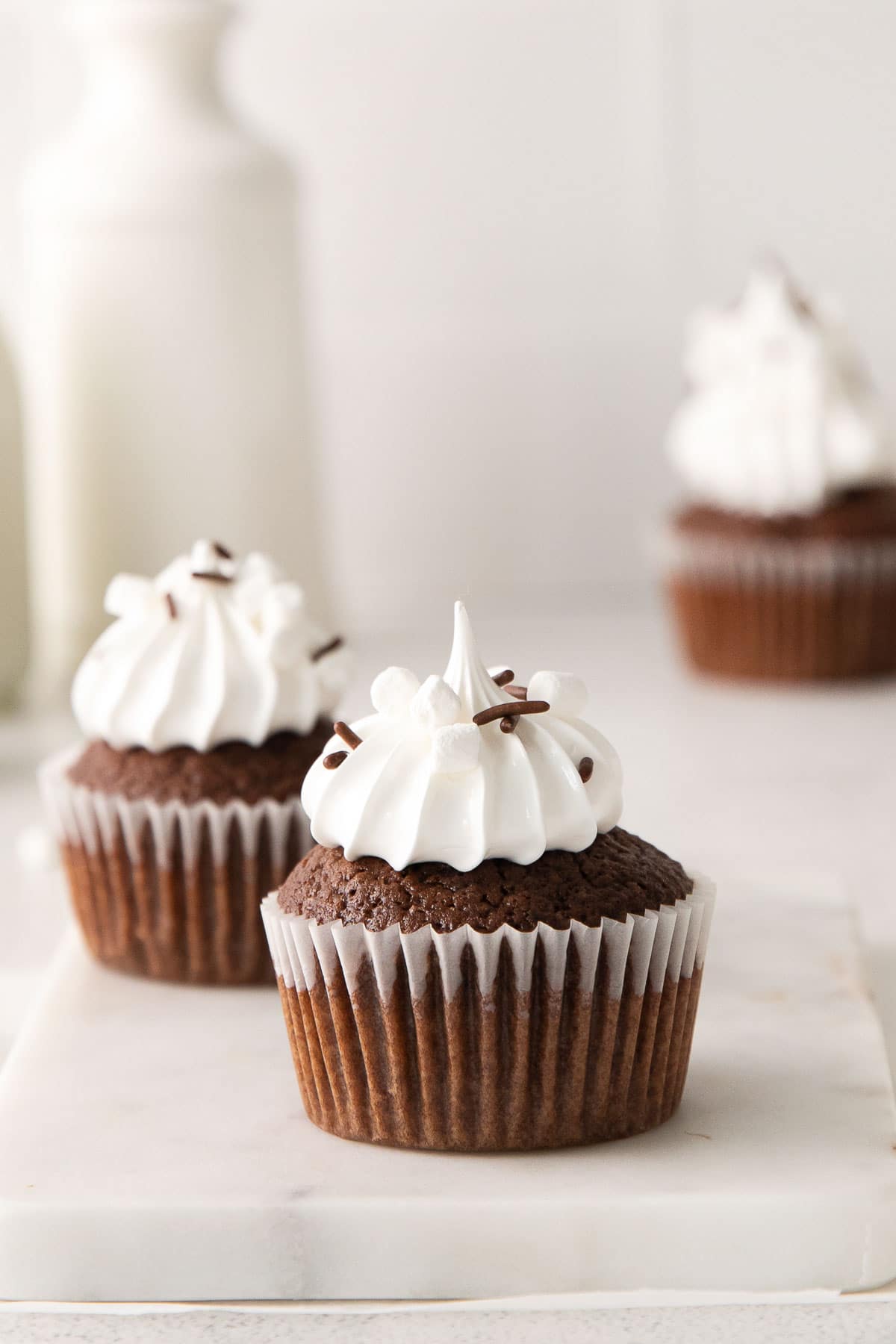 chocolate cupcake with marshmallow frosting topped with marshmallows and chocolate sprinkles