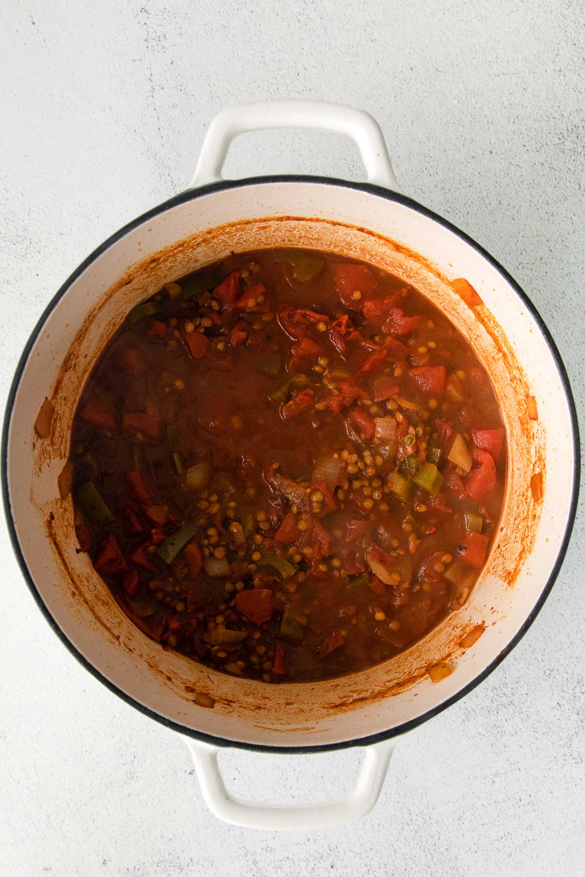 white dutch oven with lentil chili cooking