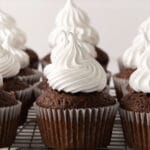 closeup of a wire rack with several chocolate cupcakes topped with white marshmallow frosting
