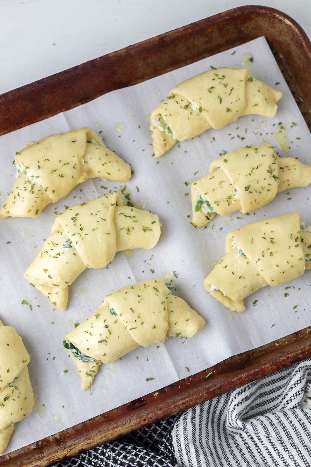 six uncooked crescent rolls on a baking sheet lined with parchment paper