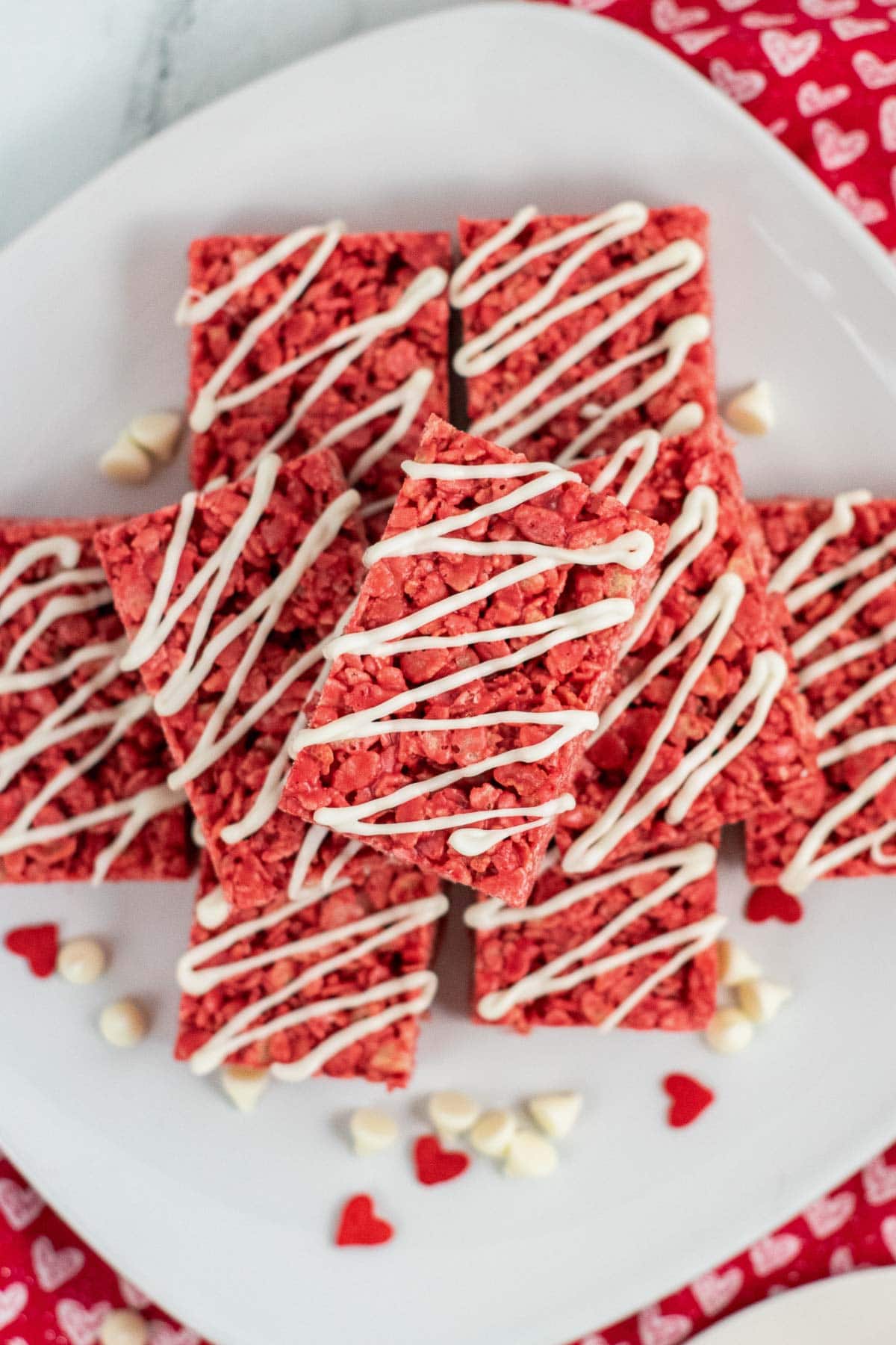 stack of red rice krispie treats with white drizzle on a white plate