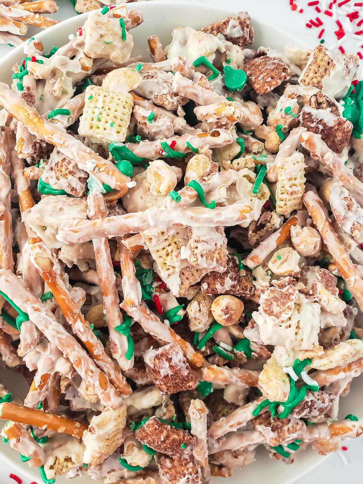 closeup of white chocolate coated chex mix with green and red spinkles