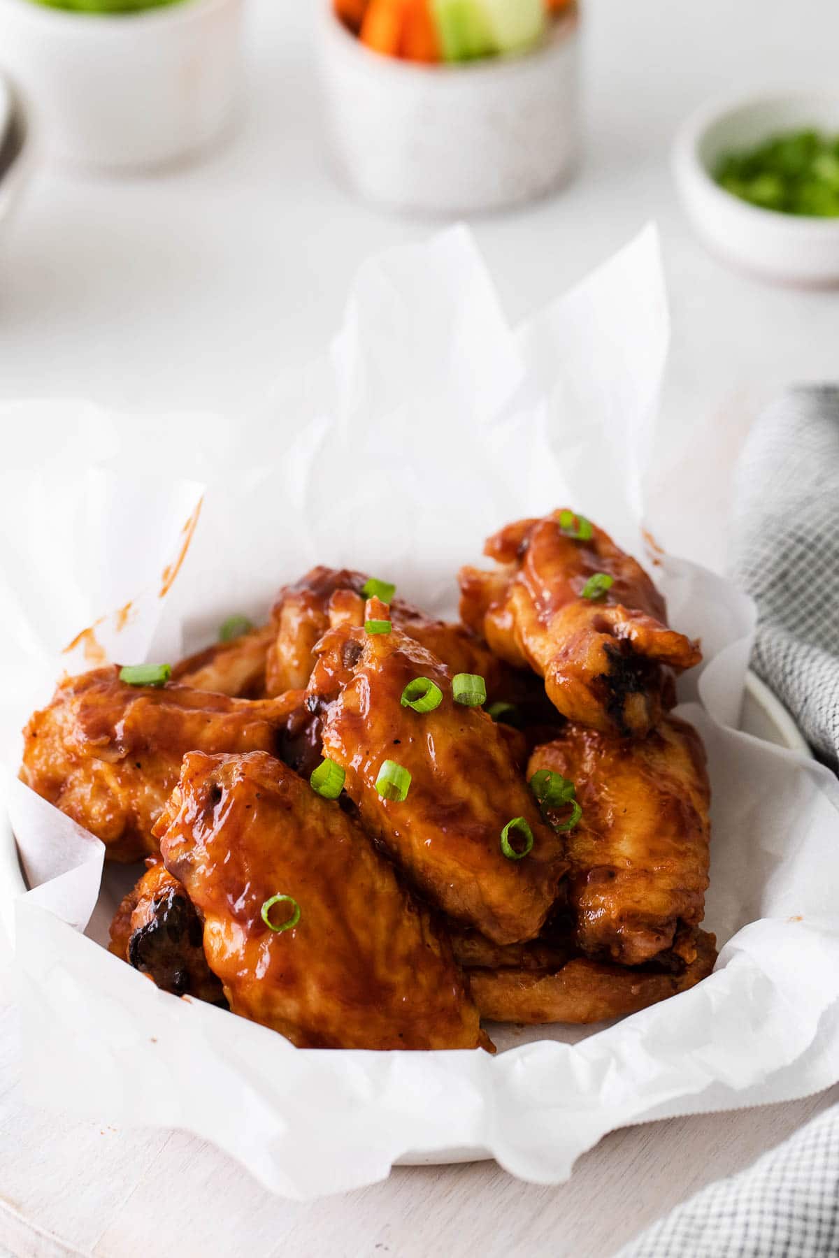 closeup of several bbq chicken wings topped with sliced green onions