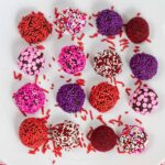 several sprinkle covered brownie truffles on a white plate