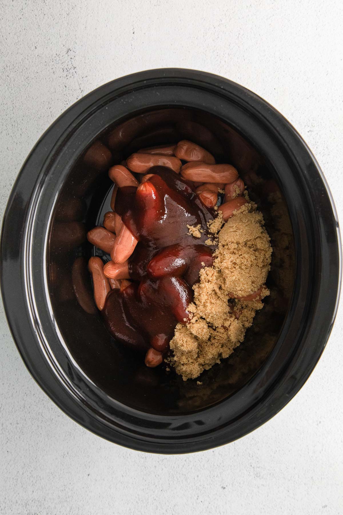 black crock pot with little weenies, brown sugar and barbecue sauce