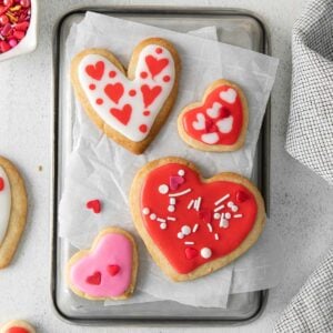 four heart shaped shortbread cookies with pink and red icing with sprinkles