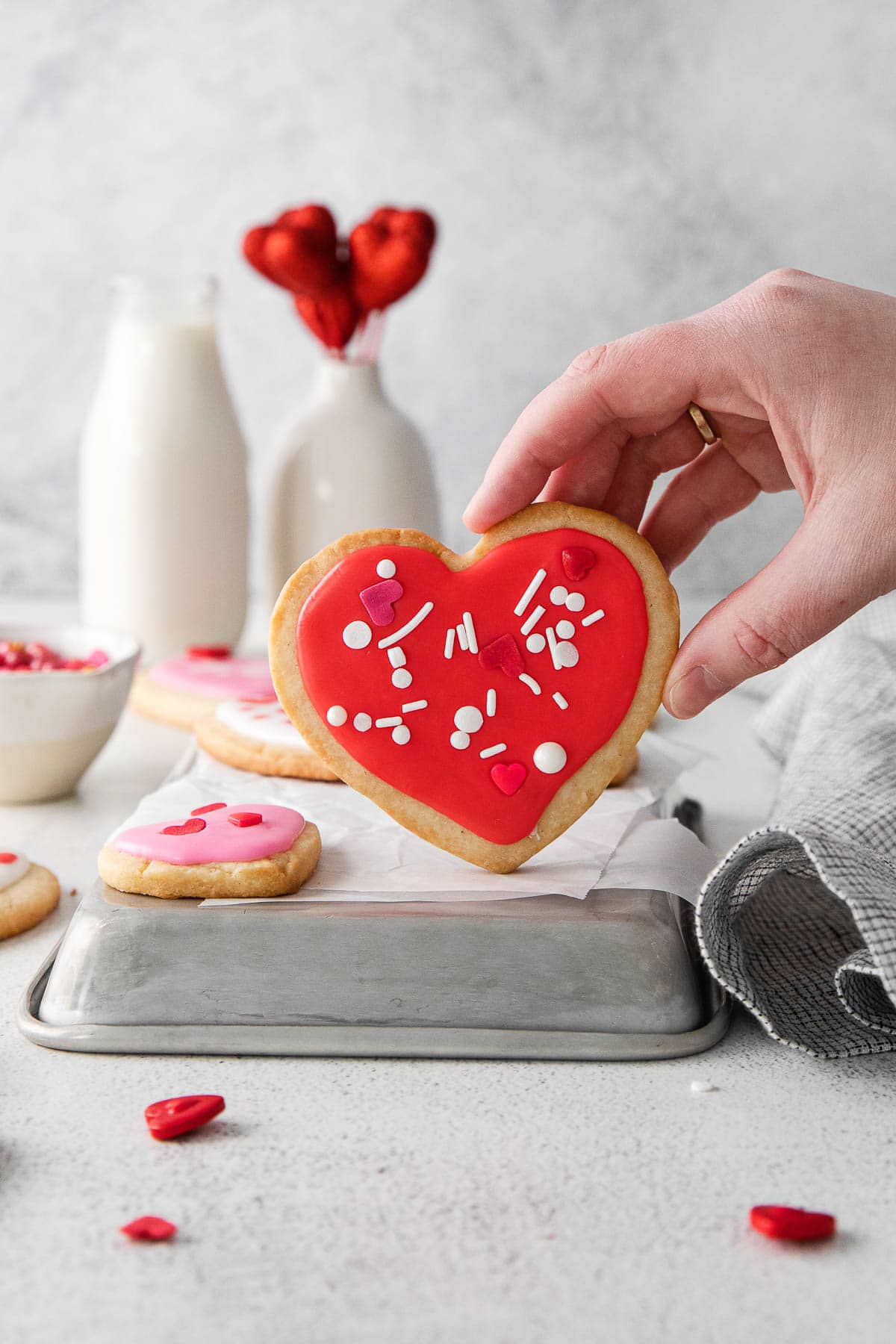 heart shaped red frosted shortbread cookies being held by a woman's hand