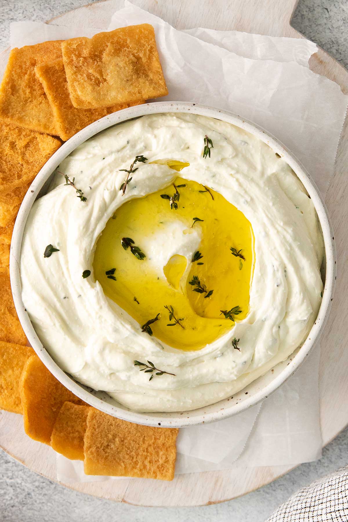 whipped feta dip topped with olive oil in a white bowl surrounded by pita chips