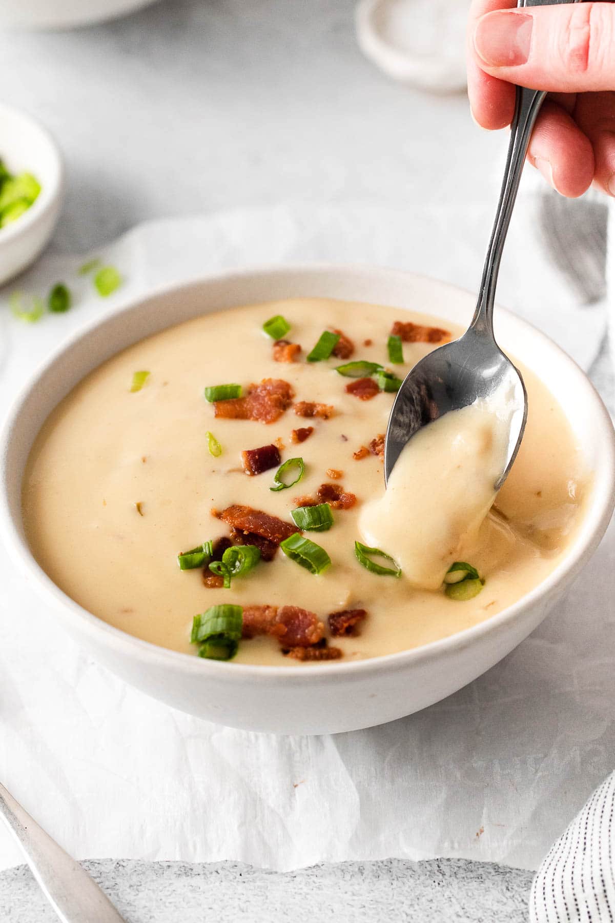 closeup of a spoon full of beer cheese soup over a white bowl of soup