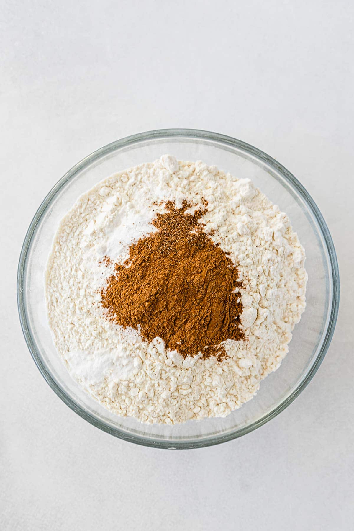 glass mixing bowl with flour cinnamon, and spices
