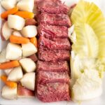 closeup of sliced corned beef, cabbage, and diced potatoes and baby carrots