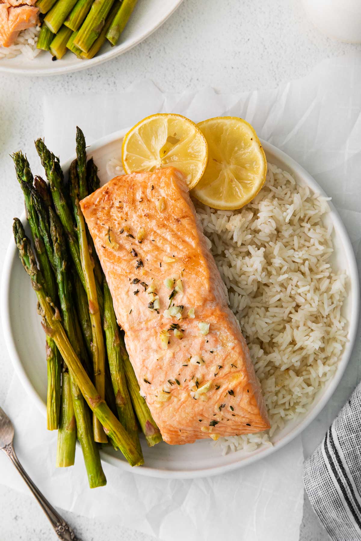 white plate with a baked salmon fillet, white rice and baked asparagus spears