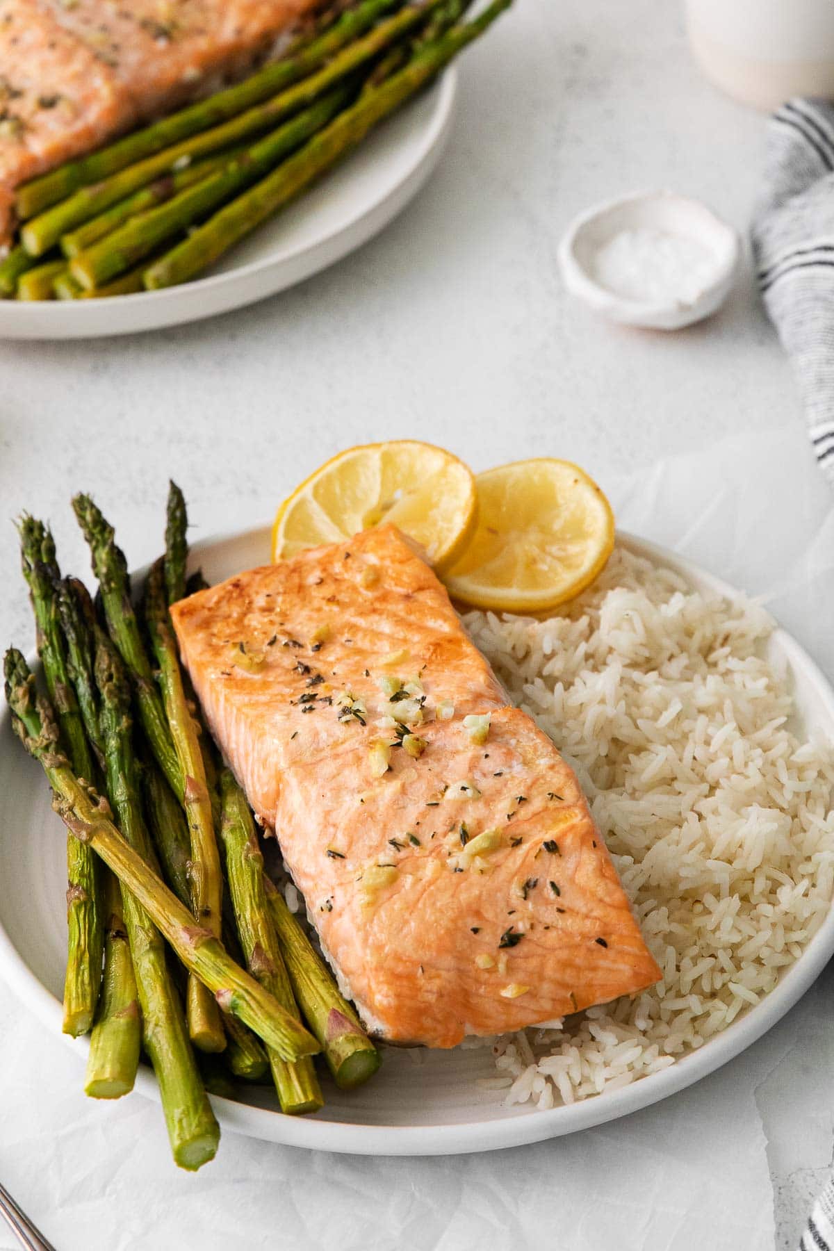 white plate with a salmon filet, asparagus and rice.