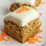 carrot cake bar topped with cream cheese frosting on a white plate